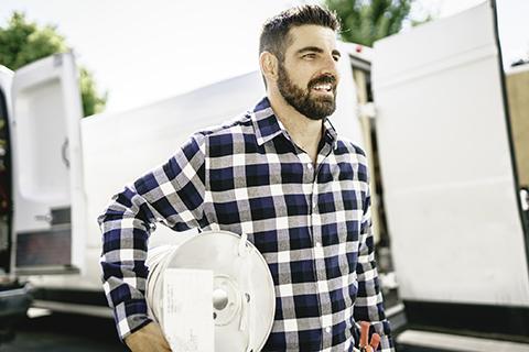 Electrician with checked shirt carrying cable
